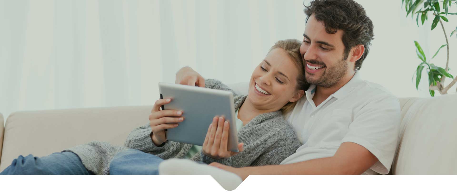 A happy couple using the tab while relaxing on a sofa